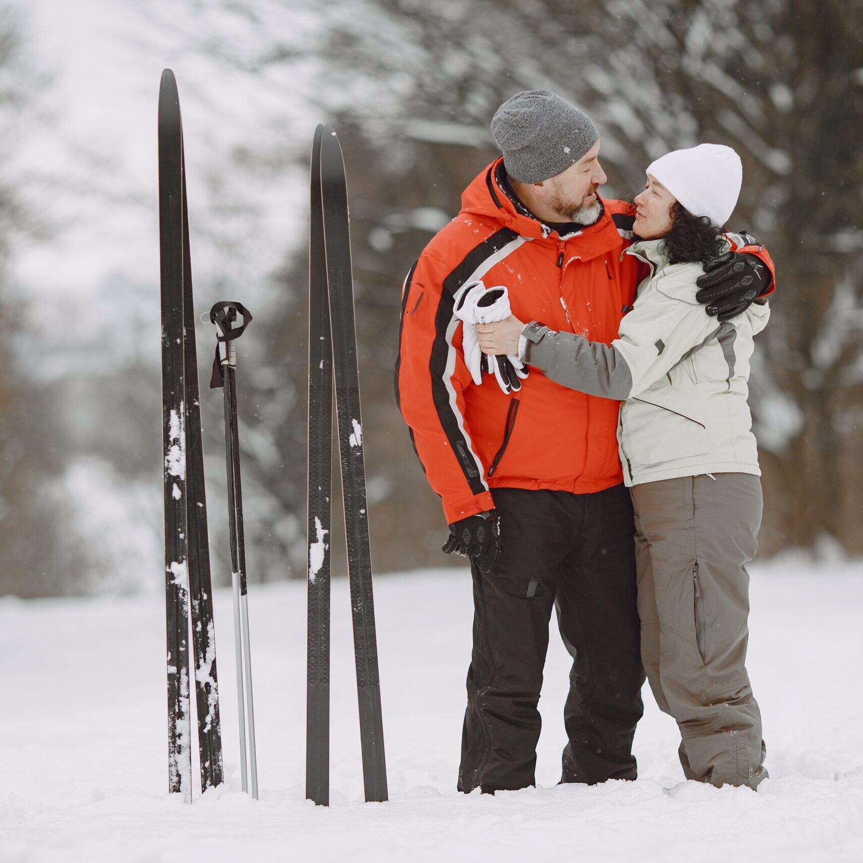 Happy mature couple in winter park. People activewear trekking or skiing in the forest at leisure