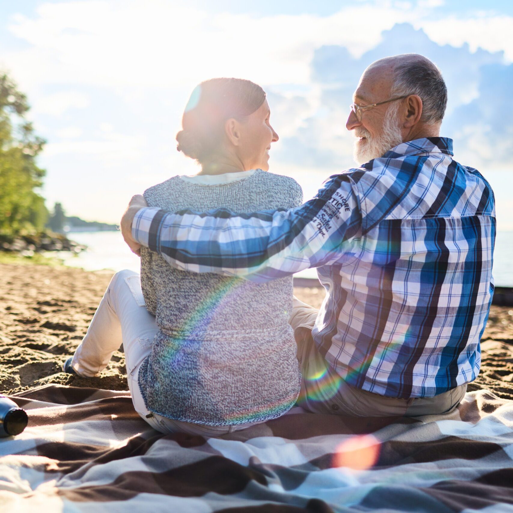 Affectionate seniors enjoying rest on sandy beach on sunny day